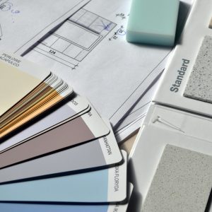 Color palette and material samples for interior renovation projects on a blueprint.